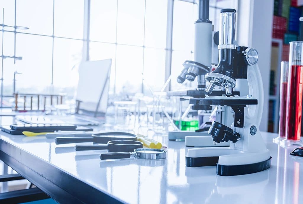 Microscopes and glassware on a bench in a bright Rameda laboratory