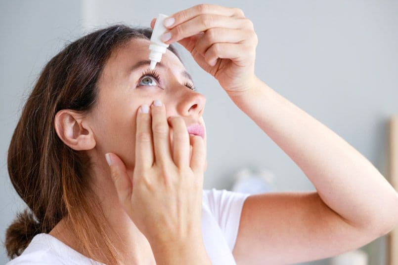 A woman applying eye drops